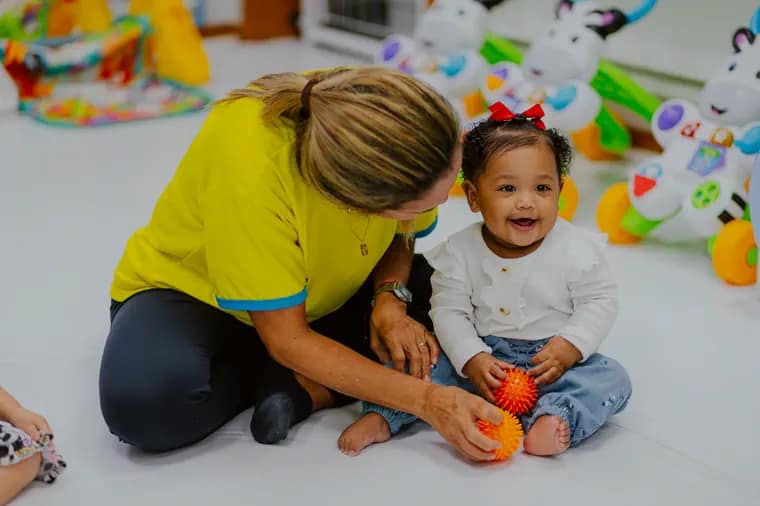 Bebê brincando com acompanhamento de uma educadora da Global Tree